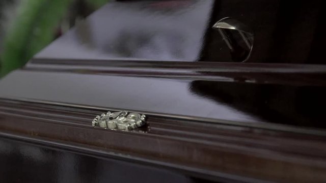 Funeral and mourning concept. Close up handheld shot of details of brown wooden coffin in church.
