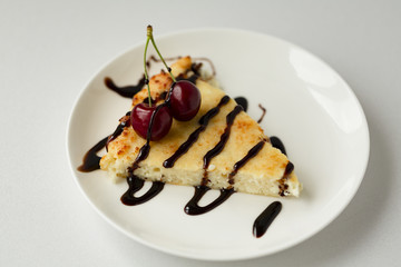 Dessert-cheesecake with cherry berries and chocolate sauce. Isolated on white