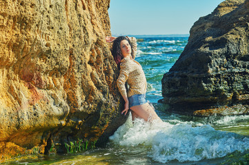 Young woman on the sea coast at the stones .