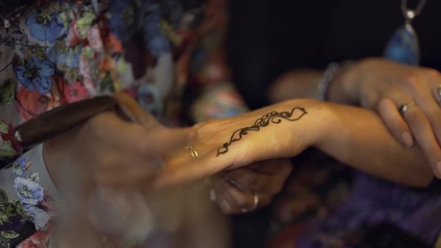 Mehndi being applied to a hand in slow motion.