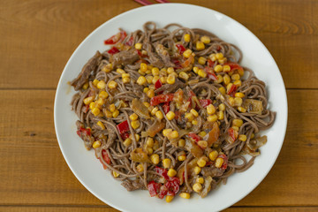 Soba noodles with beef, corn, onions and sweet peppers. Top view