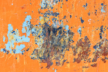 Metallic orange background with peeling paint and blue spots and rust, texture.