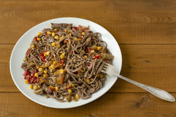 Soba noodles with beef, corn, onions and sweet peppers. Top view