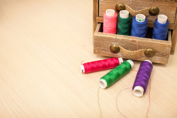 Sewing threads multicolored in wooden box background closeup with space for text