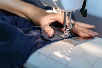 Girl sews a suit of blue cloth with the sewing machine