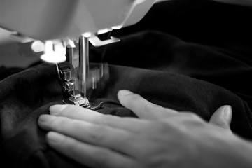 Girl sews a suit of blue cloth with the sewing machine