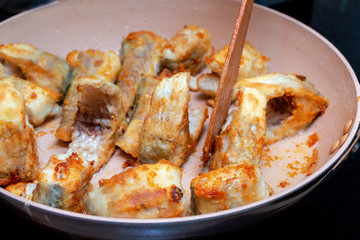 Pieces of fish fried in a hot pan