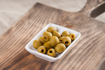 Olives in a bowl on wooden surface 