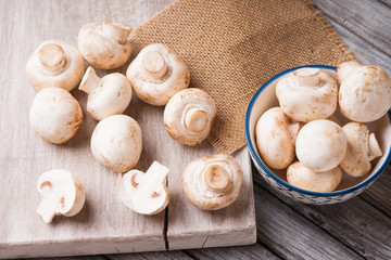 Fresh champignons on a cutting board and in a bowl 