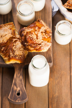 Jars with milk and bread buns on a cutting board 