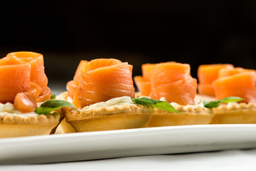 The salted smoked salmon in the basket is made in the form of a rose on a white plate