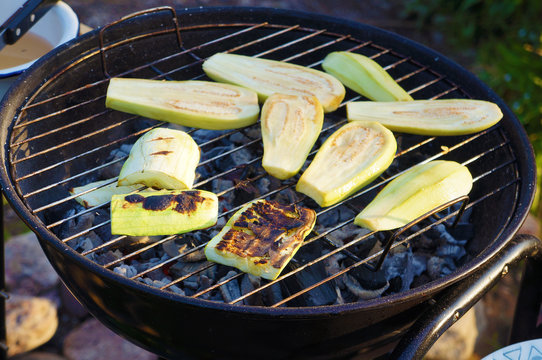 Zucchini on the lattice over the coals in a round grill