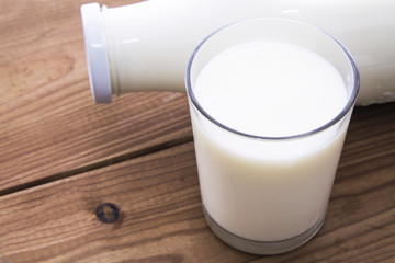 glass and bottle of milk on wooden table