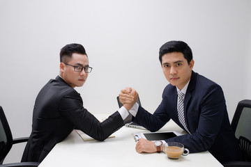 Two businessmen competing arm wrestling in office