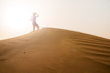 Fototapeta na wymiar Blurred figure of a traveler at the top of dune