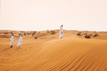 Fototapeta na wymiar Dunes in desert, sand. In the distance are men in Arab national dress