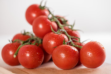 red ripe tomatoes in white bowl on white background with water drops condentation moisture 