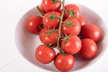 red ripe tomatoes in white bowl on white background with water drops condentation moisture 