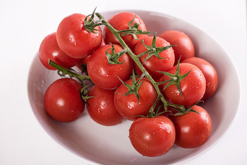 red ripe tomatoes in white bowl on white background with water drops condentation moisture 