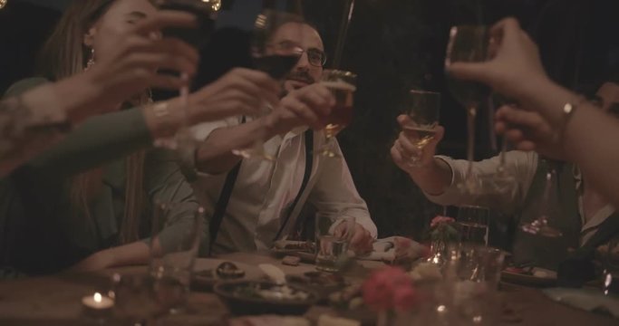 Young friends celebrating and toasting at elegant rustic dinner party