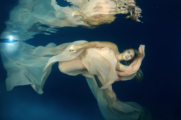 Young beautiful woman in a long dress underwater
