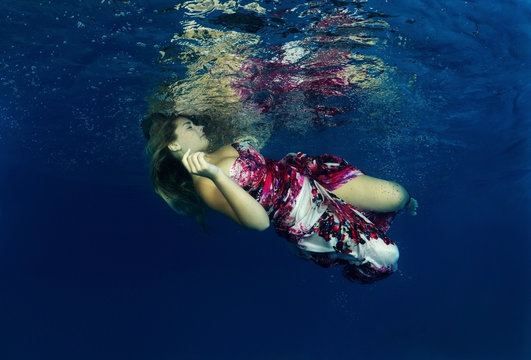 Young beautiful woman in a bright dress underwater