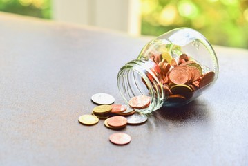 Close-Up View of a Glass Jar with Coins Spilling Out