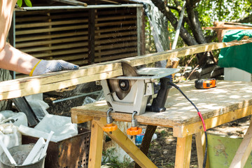 The builder cuts the board with a circular saw