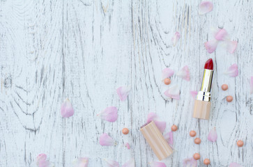 Lipsticks with rose petals on white wooden background