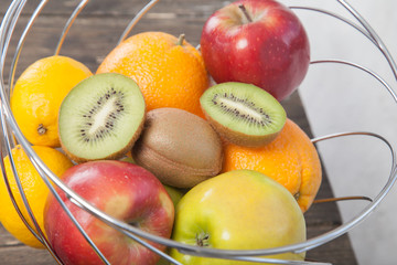 Assortment of exotic fruits close-up: kiwi, red and green apple, oranges and lemon on wooden table. Green grocery. Healthy and vegan food. Delicious fruits.