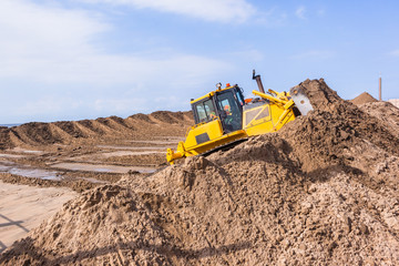 Earthworks Construction Operating Dozer Machine moving sand closeup photo.