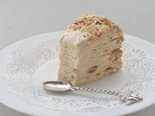 Portion of multi layered cake, cut off with funny spoon. Puff pastry cake decorated with crumbs. Selective focus.