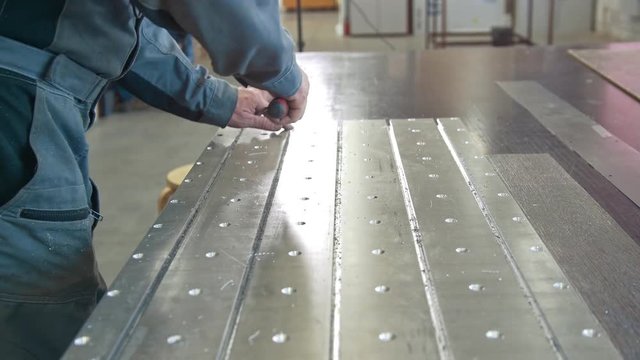Male hands makes chamfering removing burrs on metal panel with a scraper
