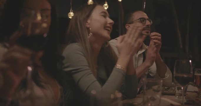 Young friends celebrating, eating and drinking at rustic dinner party