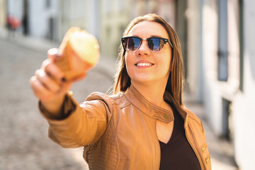 Smiling woman showing and pointing an ice cream cone at camera. Person goofing and messing around...