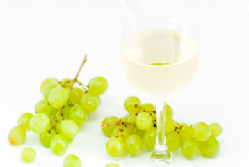 glass with white dry wine and white grapes on white background