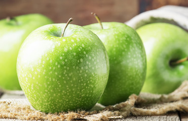 Green apples on old wood background, rustic style, selective focus