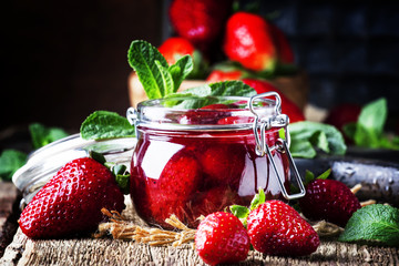 Strawberry confiture with whole berries, vintage wooden background, selective focus