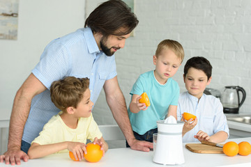 portrait of family making fresh orange juice in kitchen at home