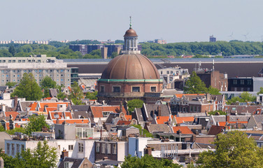 Fototapeta na wymiar Round Koepelkerk with copper dome next to Singel canal . Roofs and facades of Amsterdam. City view from the bell tower of the church Westerkerk, Holland, Netherlands.