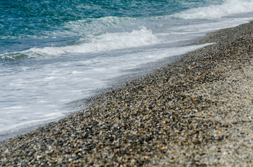 pebble beach washed by sea waves, small and various stones forming the shore