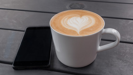 technology, business and modern life concept- close up of smartphone and coffee cup on table at cafe