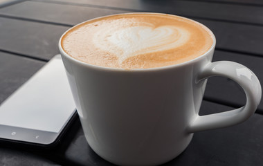 technology, business and modern life concept- close up of smartphone and coffee cup on table at cafe