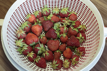 Colander with ripe strawberries, fresh berries with water drops. Concept of vegan food.