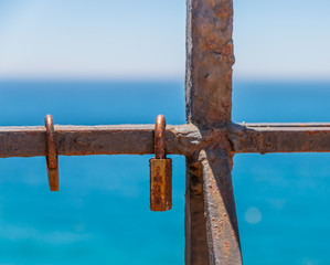Fototapeta premium rusty padlock attached to a balustrade by the sea, a traditional way of showing love