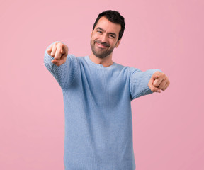 Handsome man points finger at you on pink background