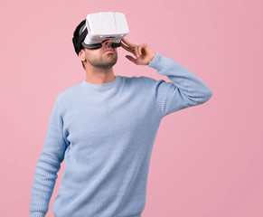 Man with blue sweater using VR glasses. Virtual reality experience on pink background