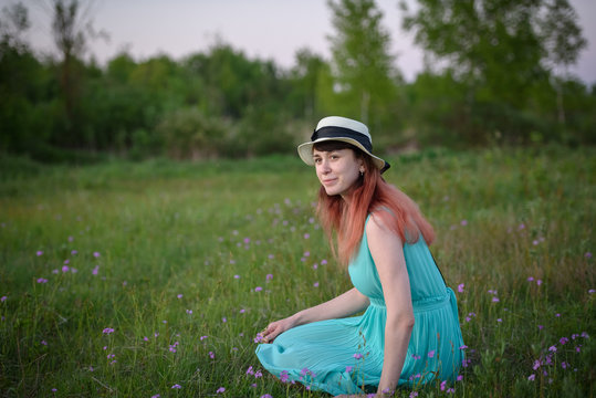 Girl in blue dress sitting in a field of flowers