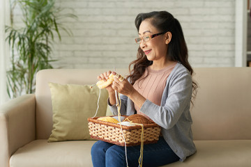 Elderly woman sitting on sofa and knitting