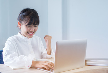 Asian Young Students or Start up Adolescents celebrate hands up after watching exam results in laptop, happy joy of accomplishing successful goal activities with expression positive emotion on campus